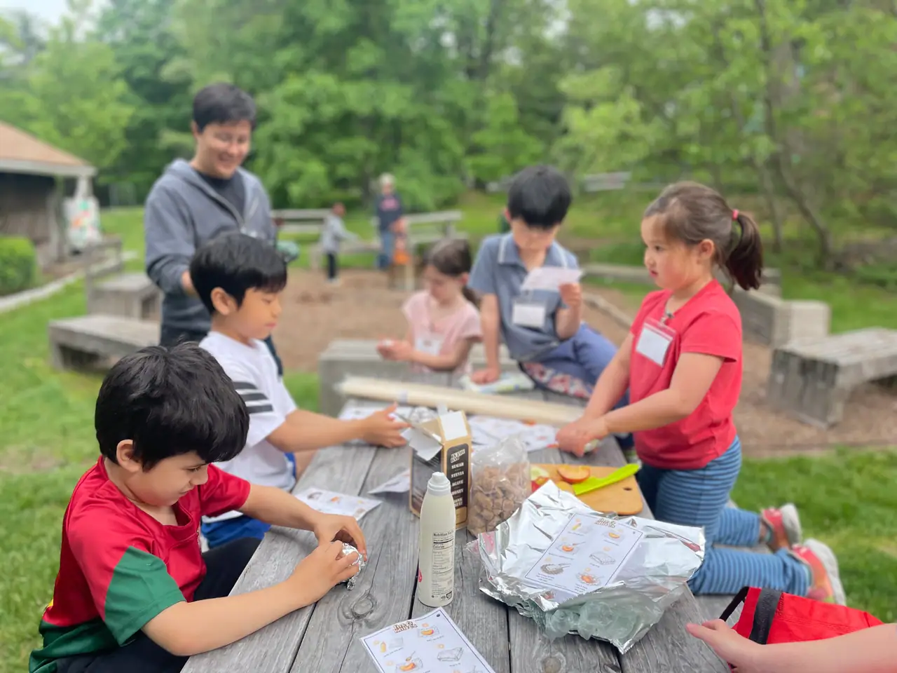 Kids at a picnic table add the skill cards they earned to their field journals.