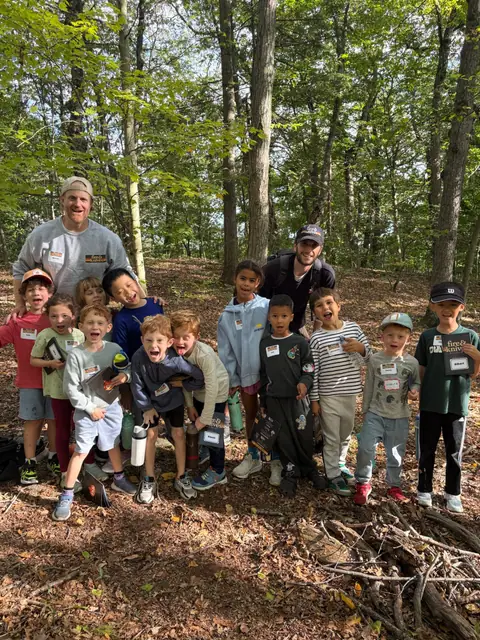 An instructor with a class of kids in the fall woods.